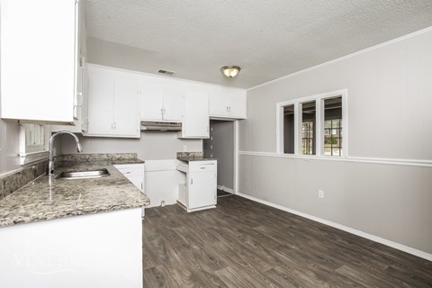 A kitchen with white cabinets and a granite countertop.