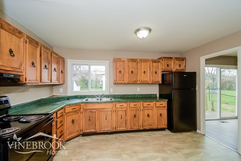 A kitchen with wooden cabinets and a black refrigerator.