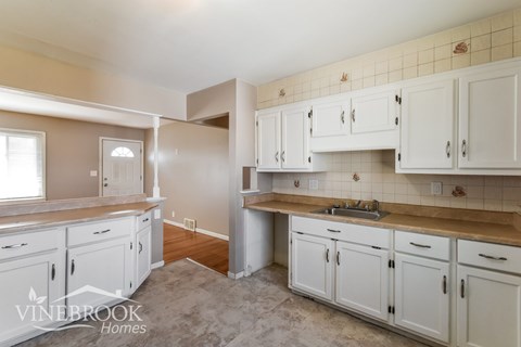 A kitchen with white cabinets and a counter top.