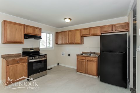 A kitchen with wooden cabinets and black appliances.