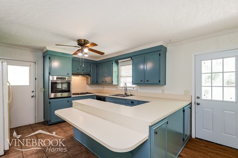 A kitchen with blue cabinets and a white countertop.