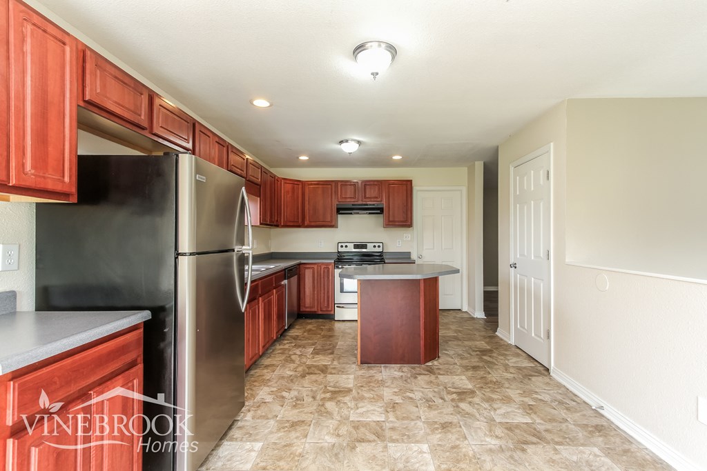 A kitchen with a black refrigerator and wooden cabinets.