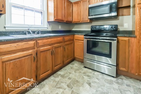 A kitchen with wooden cabinets and a black stove top oven.