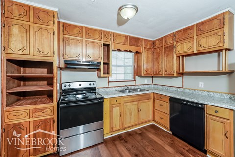 A kitchen with wooden cabinets and a black stove top oven.