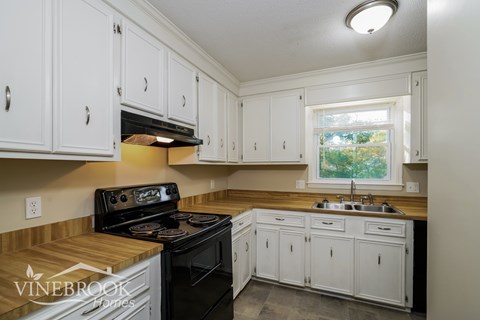 A kitchen with white cabinets and a black stove top oven.