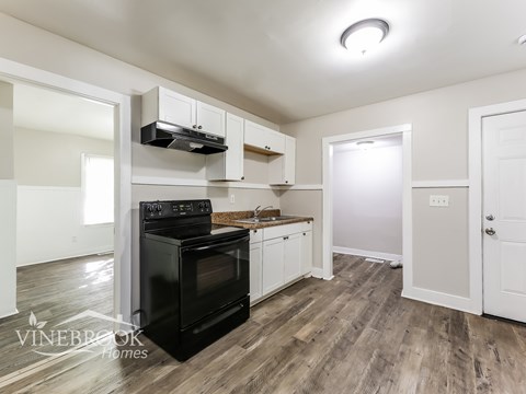 A black stove top oven in a kitchen with wood flooring.
