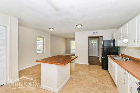 A kitchen with a wooden counter top and white cabinets.