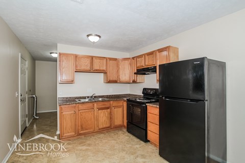 A kitchen with black appliances and wooden cabinets.