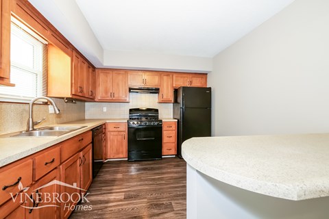 A kitchen with wooden cabinets and a black refrigerator.