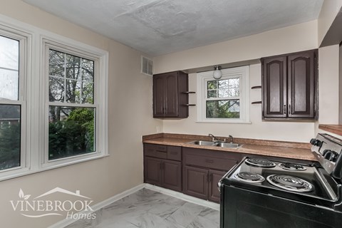 A kitchen with a black stove top oven and wooden cabinets.