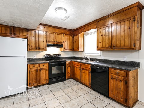 A kitchen with wooden cabinets and black countertops.