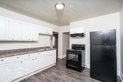 A kitchen with black appliances and white cabinets.