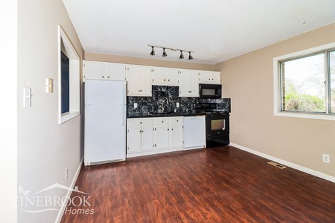 A kitchen with white appliances and wooden floors.