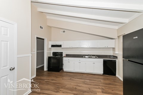 A kitchen with white cabinets and black appliances.