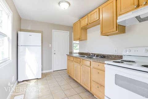 A kitchen with wooden cabinets and a white stove top oven.