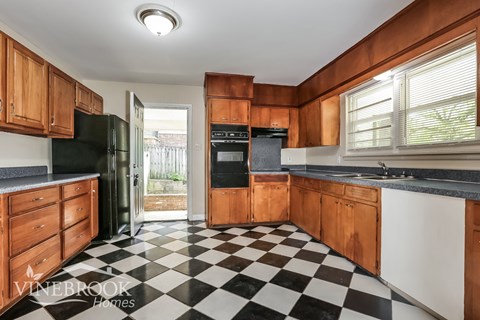 A black and white checkered floor in a kitchen with wooden cabinets.