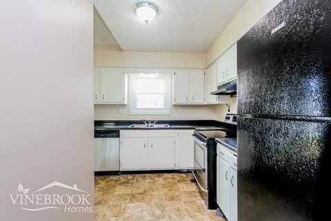 A kitchen with a black refrigerator and white cabinets.