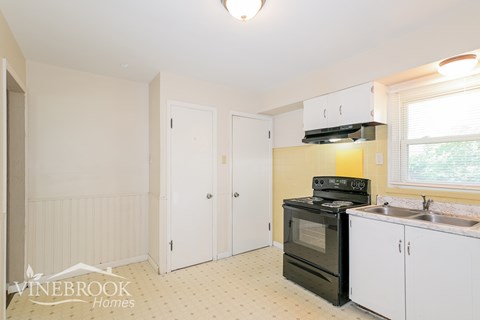 A kitchen with a black stove top oven and white cabinets.