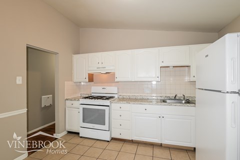 A kitchen with white appliances and cabinets.