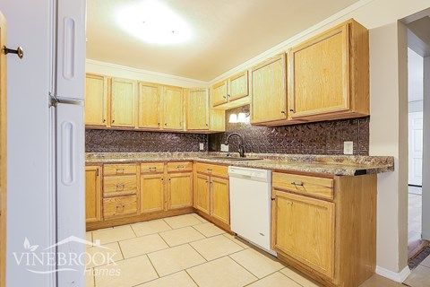 A kitchen with wooden cabinets and a white dishwasher.