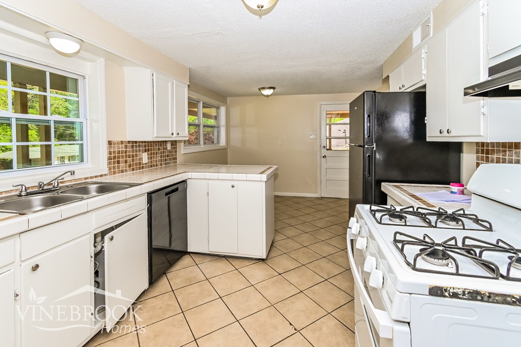 A kitchen with white cabinets and a black refrigerator.
