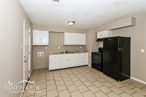 A kitchen with white cabinets and a black refrigerator.
