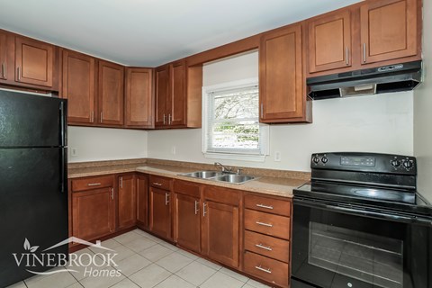 A kitchen with brown cabinets and a black refrigerator.