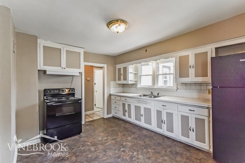 A kitchen with a purple refrigerator and a black stove top oven.