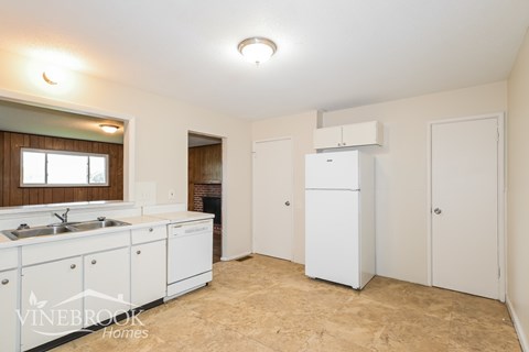 A kitchen with white cabinets and a Vinebrook Homes logo.