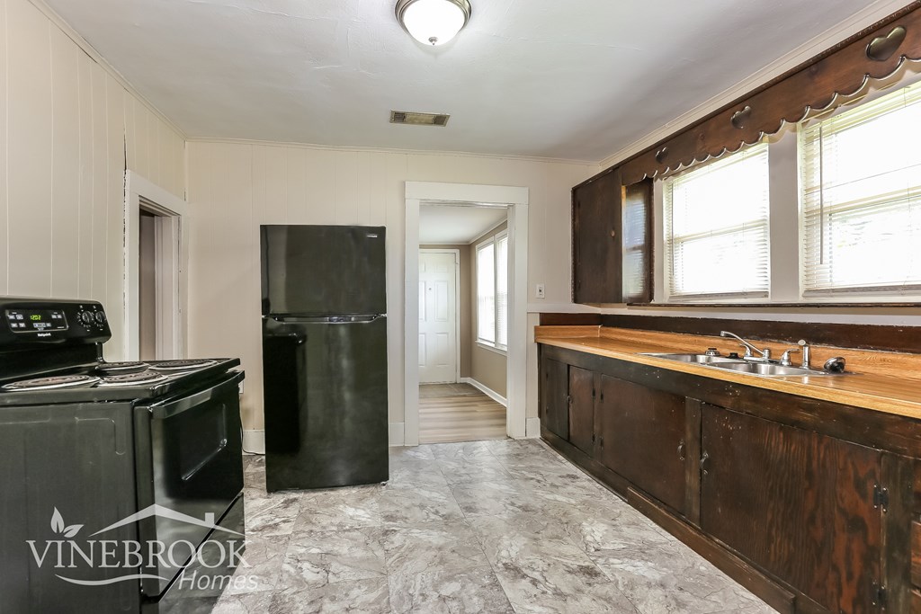 A kitchen with a black stove top oven and black refrigerator.