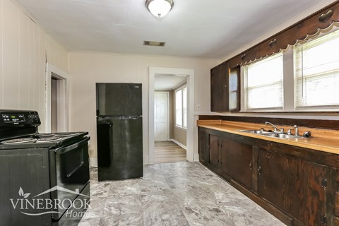 A kitchen with a black stove top oven and black refrigerator.