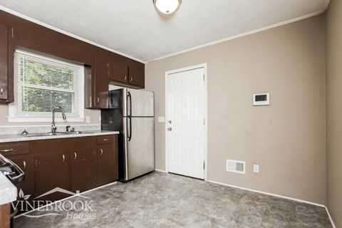 A kitchen with brown cabinets and a white fridge.