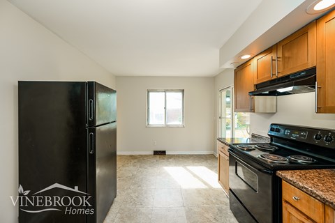 A kitchen with a black fridge and a black stove top oven.