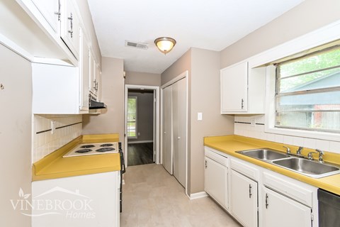 A kitchen with white cabinets and a yellow stove top.