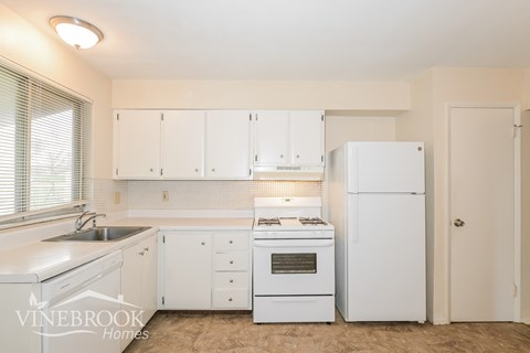 A white kitchen with a sink, stove, and refrigerator.