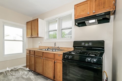 A black stove in a kitchen with wooden cabinets.
