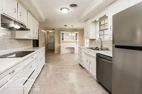 A modern kitchen with white cabinets and a stainless steel refrigerator.