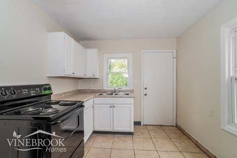 A kitchen with a stove top oven and a window.
