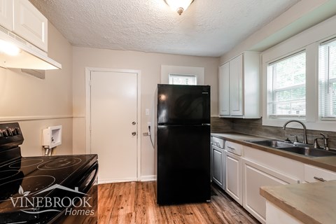A kitchen with a black fridge and a stove top oven.