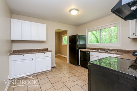 A kitchen with white cabinets and a black refrigerator.