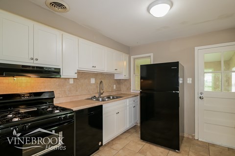 A kitchen with black appliances and white cabinets.