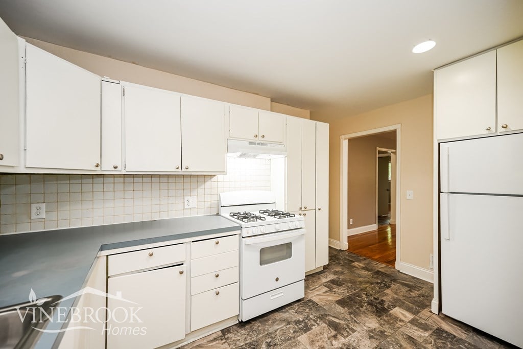 A kitchen with white cabinets and a tiled backsplash.