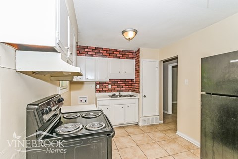 A kitchen with a black stove top oven and white cabinets.