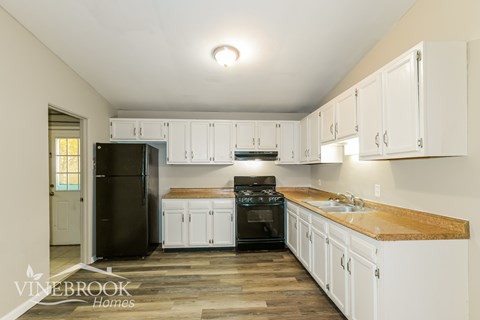 A kitchen with white cabinets and a black refrigerator.