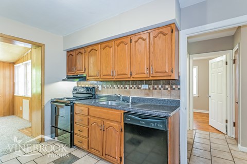A kitchen with wooden cabinets and a black stove top oven.