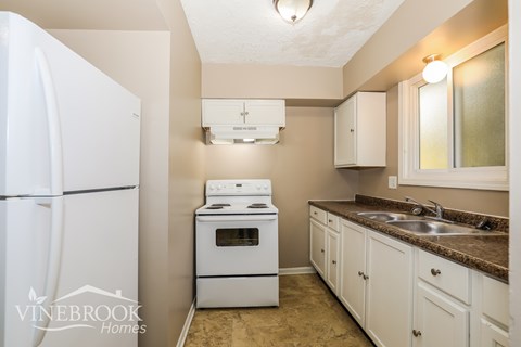 A small kitchen with a white refrigerator and a white stove top oven.