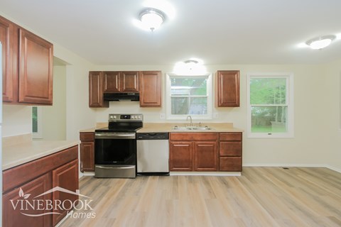 A kitchen with wooden cabinets and a Vinebrook Homes logo.