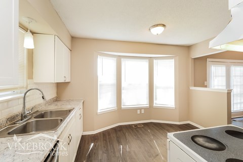 A kitchen with a sink, stove, and cabinets.