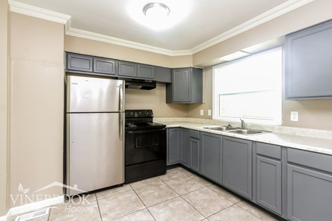 A kitchen with a stainless steel refrigerator and a black oven.