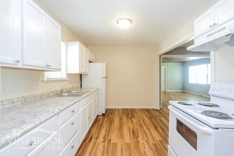 A kitchen with white cabinets and a white stove top oven.